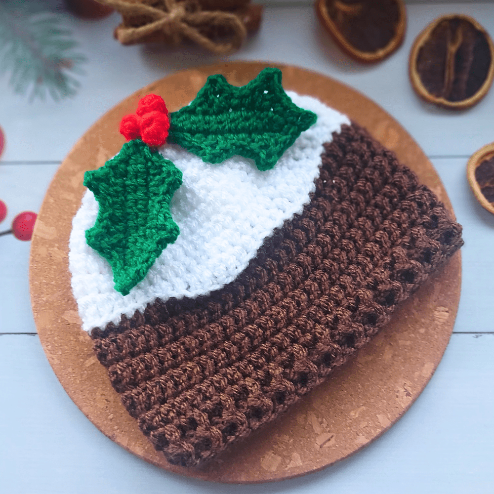 Christmas pudding novelty festive crochet beanie hat, a white top resembling brandy or rum sauce followed by dark brown for the pudding then garnished with green holly leaves and red berries