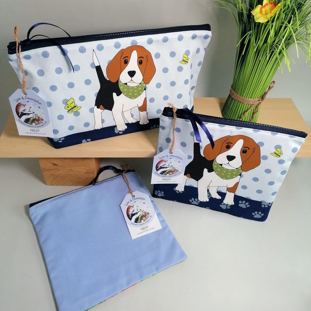 Large and medium size toiletries bags featuring a cute beagle puppy wearing a bandana with his green butterfly friends. The design has a pawprint base and spotty background