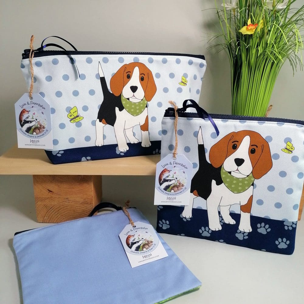 Large and medium size toiletries bags featuring a cute beagle puppy wearing a bandana with his green butterfly friends. The design has a paw print base and spotty background