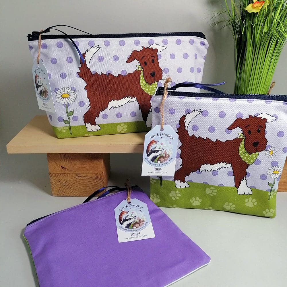 Cotton toiletries bag in large and medium sizes featuring a sweet little dog in his best bandana. Various shades of purple spotty background, green paw print base and a pale purple back.