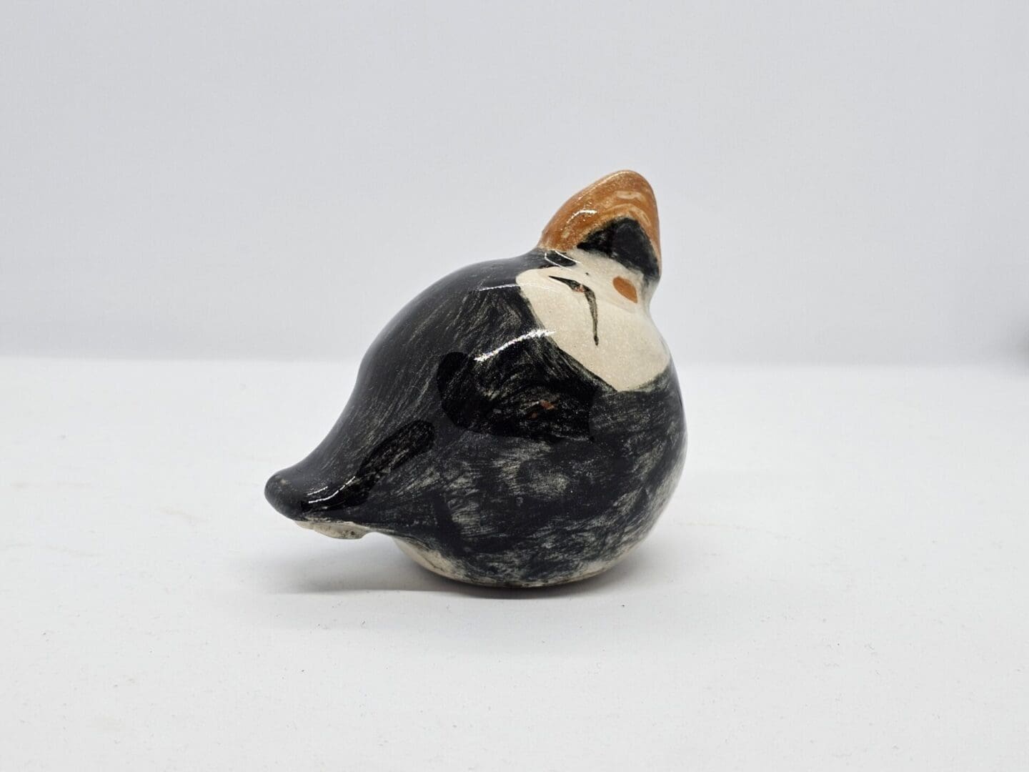 On a white background, a rear-right facing view of a ceramic puffin