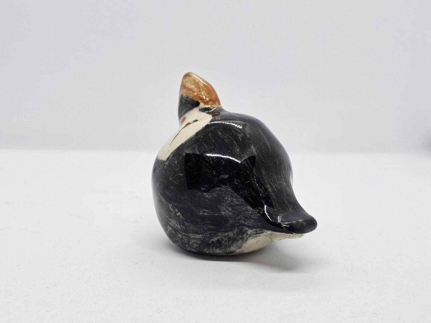 On a white background, a rear-left facing view of a ceramic puffin