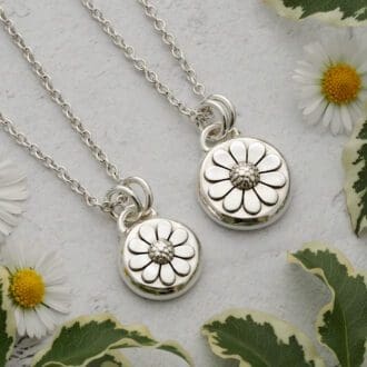Two round argentium sterling silver pebble pendants featuring a daisy flower in relief