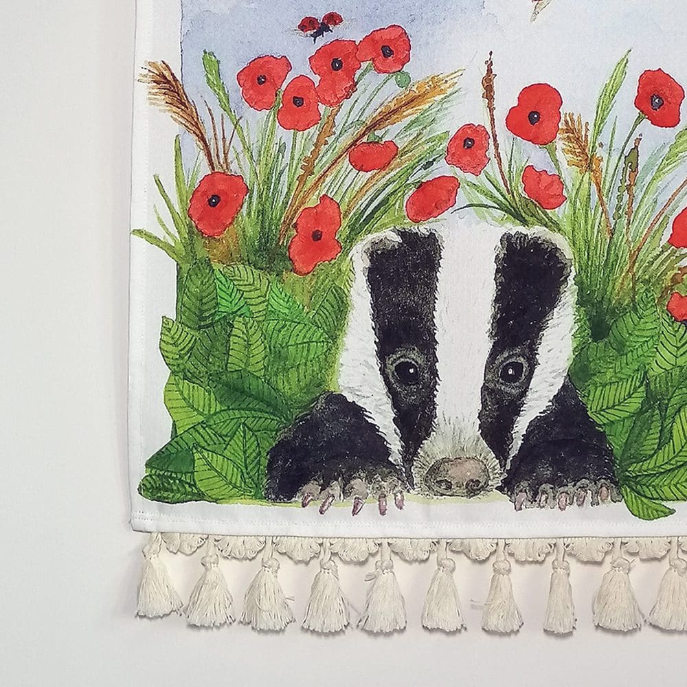 Close up detail of the badger and poppies wall hanging - printed heavy weight cotton fabric and pale cream tassels. Original illustration created as a watercolour painting.