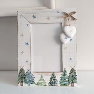 6 x 4 whitewashed frame decoupaged with a Christmas tree scene and stars design and finished with two hearts hanging from a twine bow