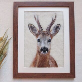 A needle felted wool picture of a roe deer buck in a dark wood effect frame.