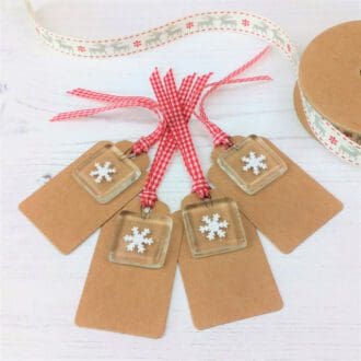 Four Kraft gift tags each with a handmade fused glass and paper cut snowflake keepsake
