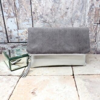 A reversible fold over zip top clutch in a silver faux leather and a grey jumbo cord.