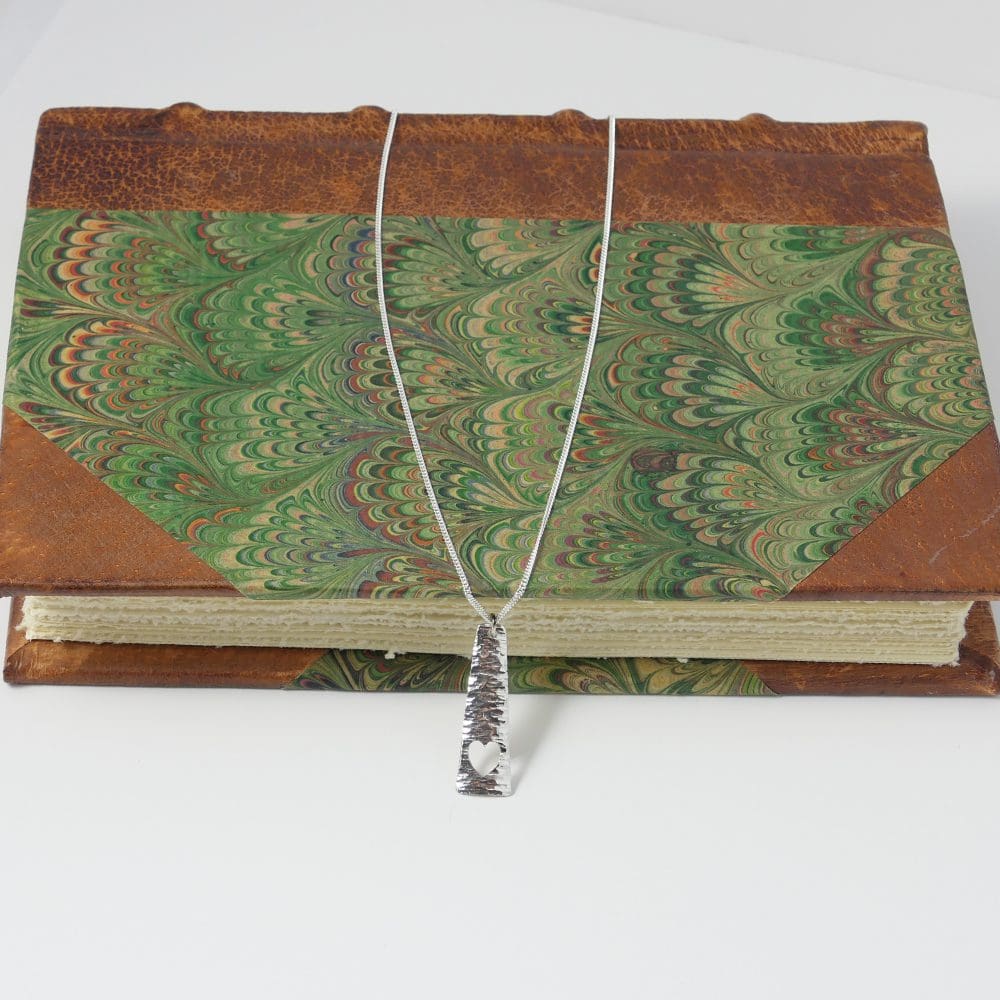 Silver-triangle-bar-heart-pendant-and-chain-laying-over-a-book