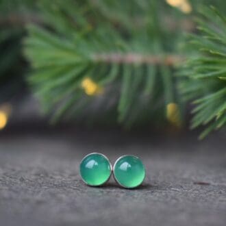 green gemstone round stud earrings with christmas foliage and lights in background