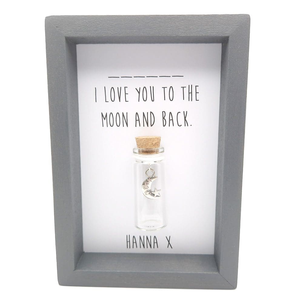 Small grey frame with a glass bottle containing a silver moon and stars charm in the centre, with a personalised i love you to the moon and back quote