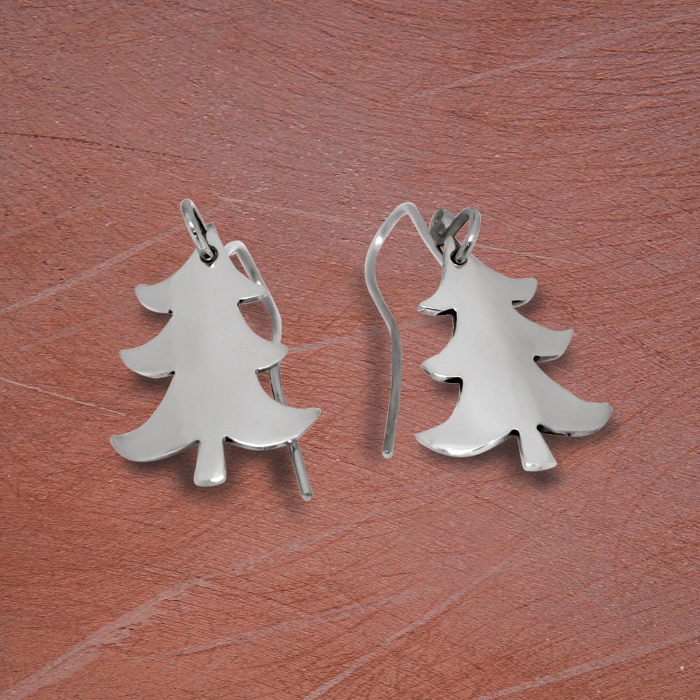 recycled-sterling-silver-christmas-tree-drop-earrings-on-a-textured-surface