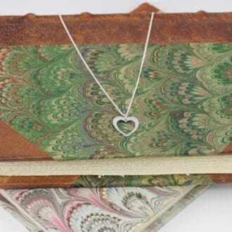 recycled-sterling-silver-heart-in-heart-pendant-and-chain-laying-on-the-cover-of-a-book