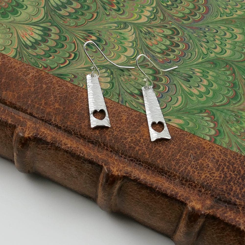 triangular-heart-earrings-on-the-leather-spine-a-green-marbled-book-cover