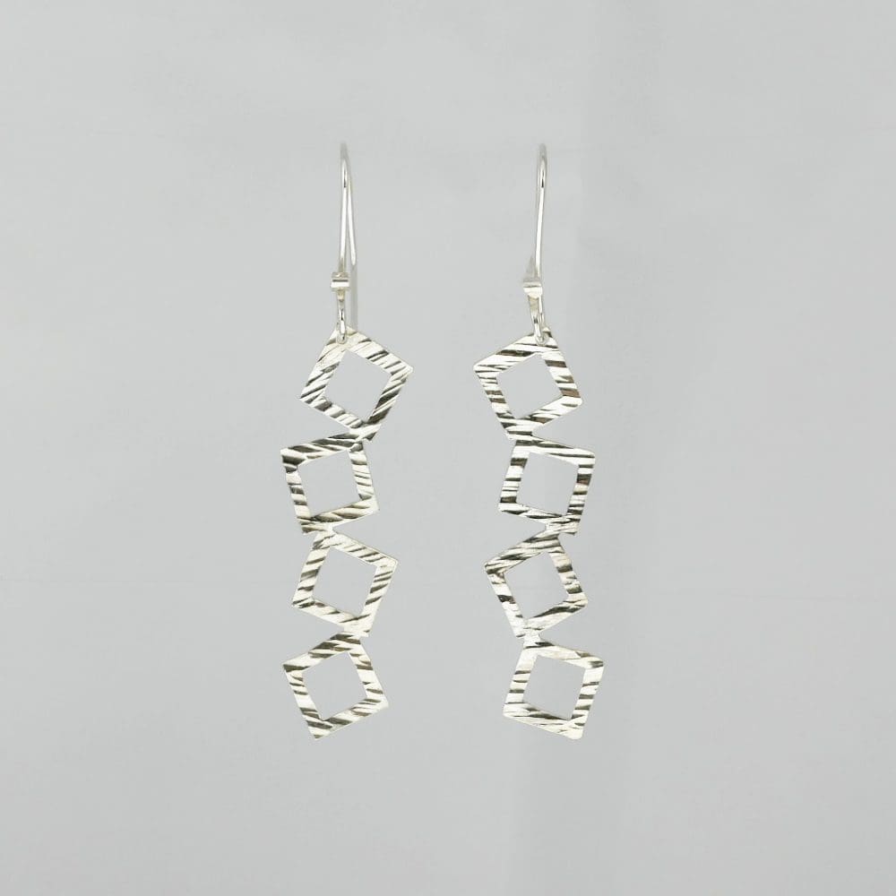 tumbling-squares-drop-earrings-hanging-on-a-white-background