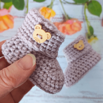 handmade crochet baby booties with a foilded cuff and a teddy bear button attached for decoration, there are vaious colours available to choose from