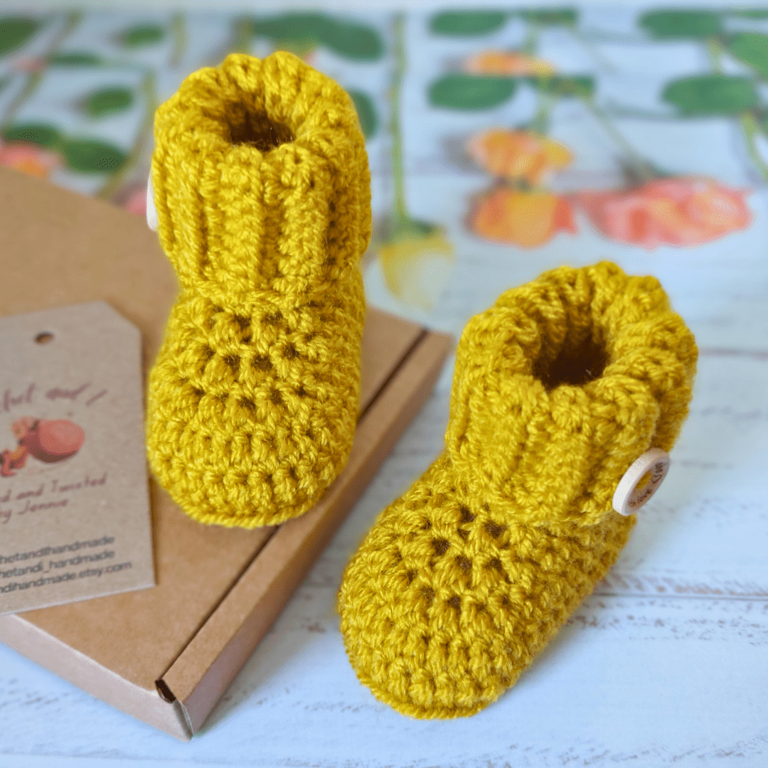 Mustard yellow coloured crochet baby booties with a ribbed folded cuff and finished off with a handmade with love wooden in sizes newborn, 0-3 and 3-6 monthsbutton