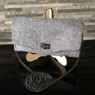 A grey linen clutch handbag featuring a chunky gun-metal chain