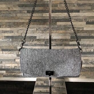 Grey linen clutch handbag with a chunky gun-metal chain hanging from a stand