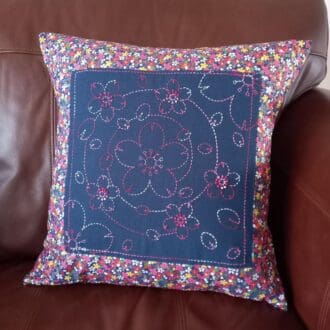 A pink and blue hand embroidered cushion