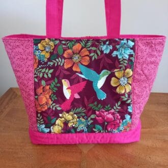 A colourful quilted tote bag with a hummingbirds design