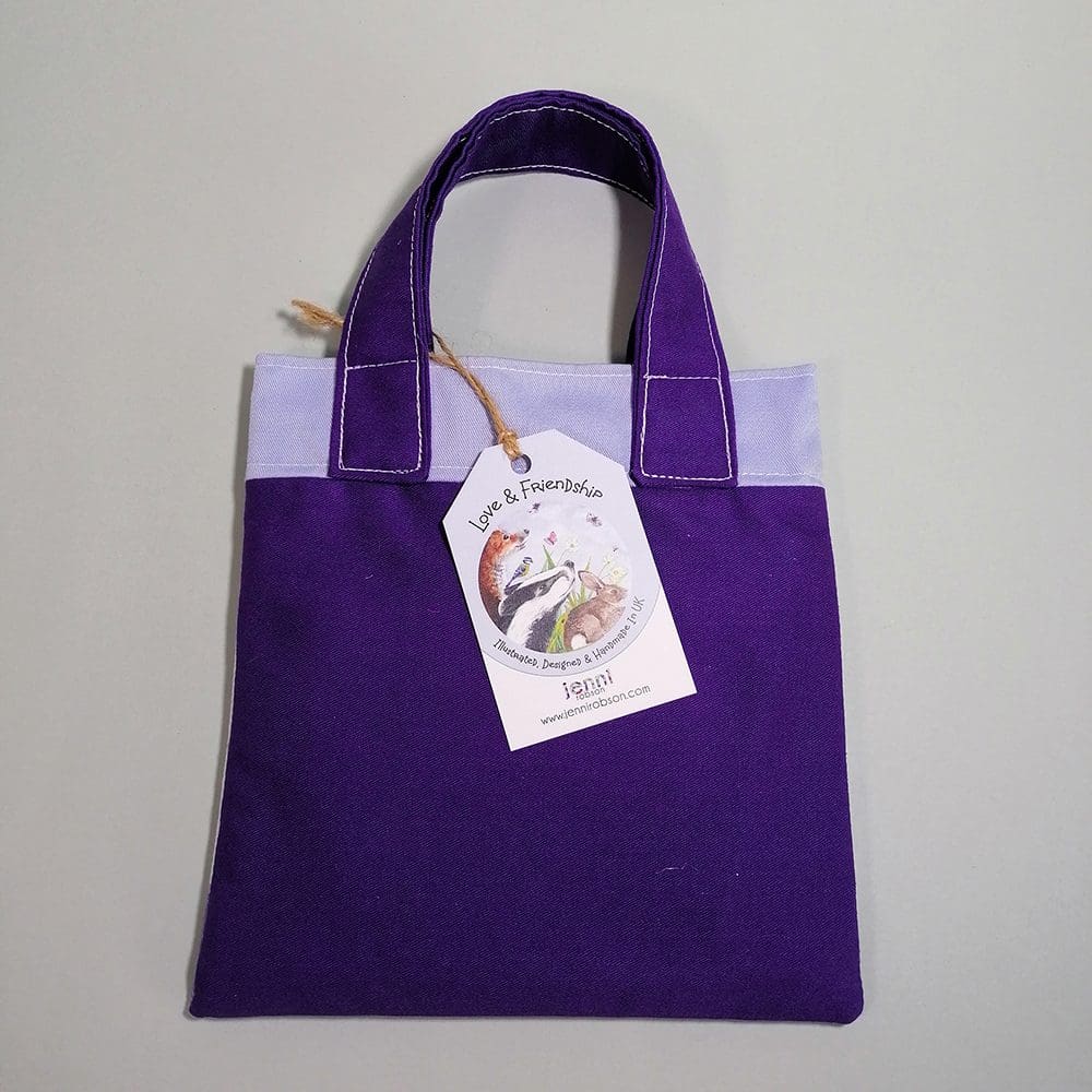 Back view of the mini bookbag in dark purple and pale blue cotton fabric. Lined with water resistant lining