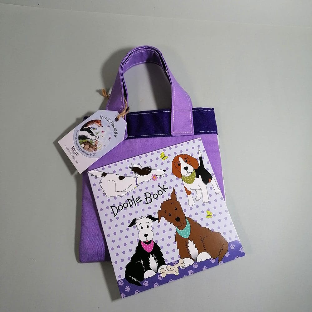 Gorgeous pale and dark purple cotton bookbag with water resistant lining featuring a smart brown dog in his best green bandana illustration. A stapled blank 20 page sketchbook featuring a selection of dogs and furry friends, fits neatly in the bag with the colouring pencils