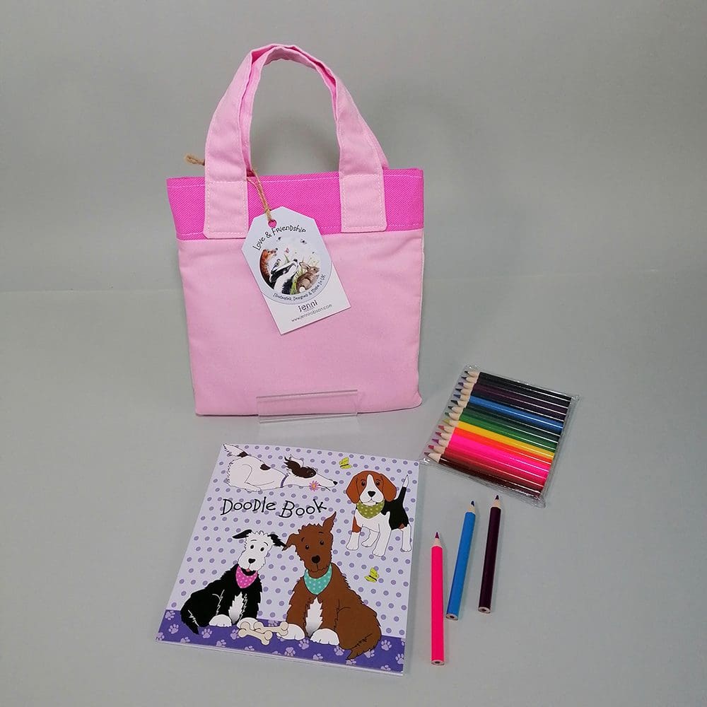 Back view of the two shades of pink mini bookbag that contains a sketchbook, colouring pencils and a bookmark for kids