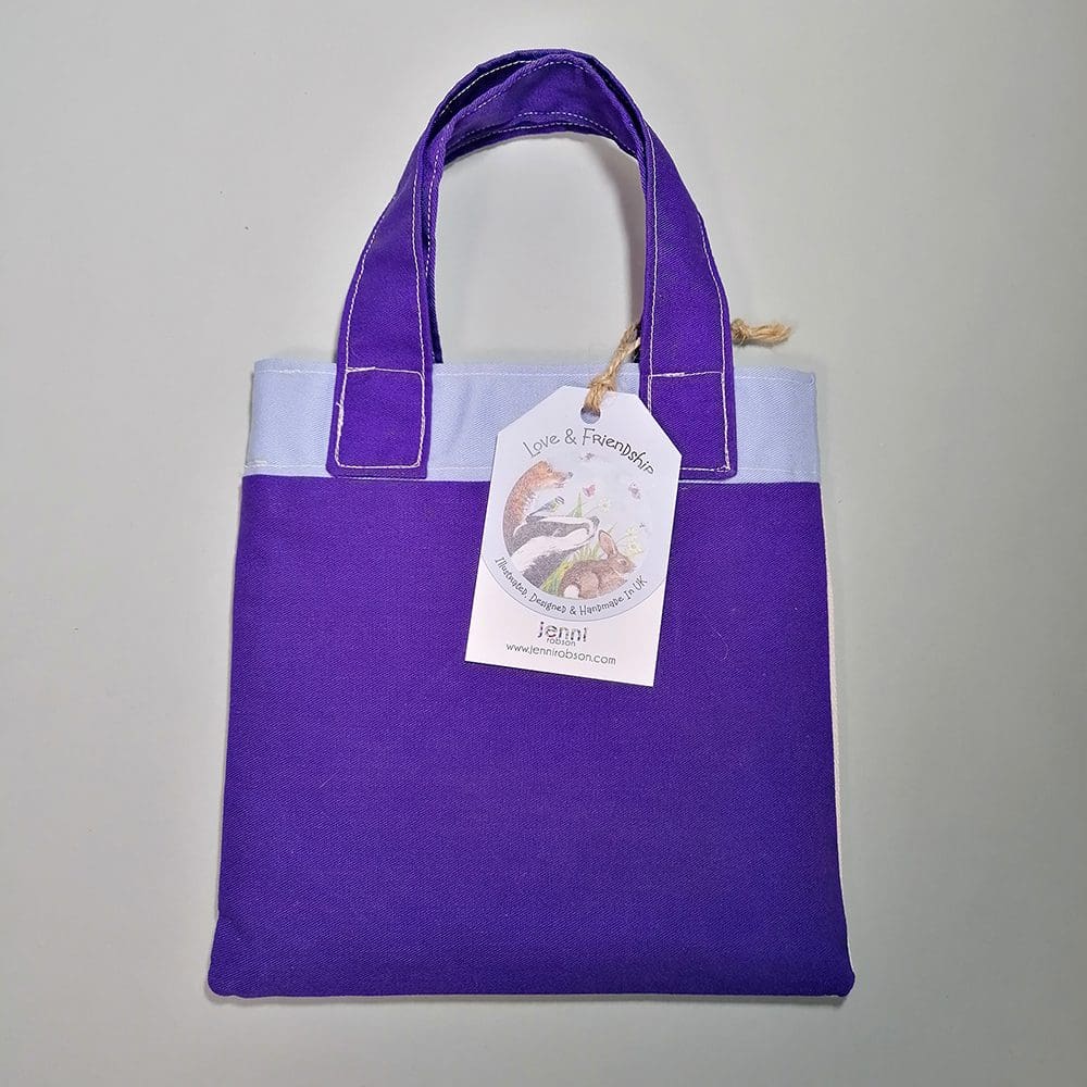 Sweet dark purple and pale blue cotton handbag water resistant lining featuring Casper butterfly and Frank Caterpillar illustration. The bag contains a stapled blank 20 page sketchbook featuring a selection of dogs and furry friends, 14 mini colouring pencils with a laminated bookmark printed with Casper and caterpillar friend. Ideal for kids who love to draw.