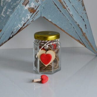 Glass Jar of clay hearts set on pegs to hang photos on the wall