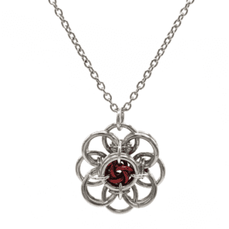 A chainmaille pendant in the shape of a flower. Silver rings make up the petals and there are coloured rings in the center.