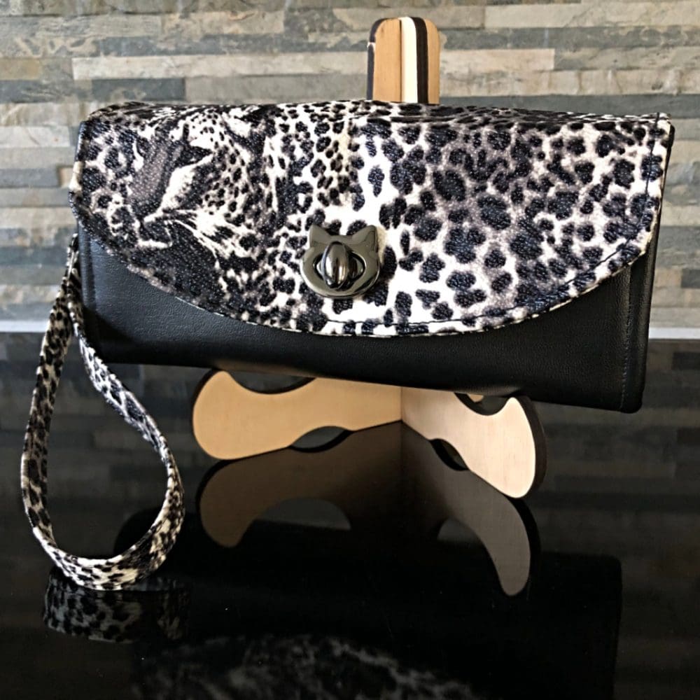 Ladies clutch wallet in faux leather featuring Leopard print flap and black body on a stand