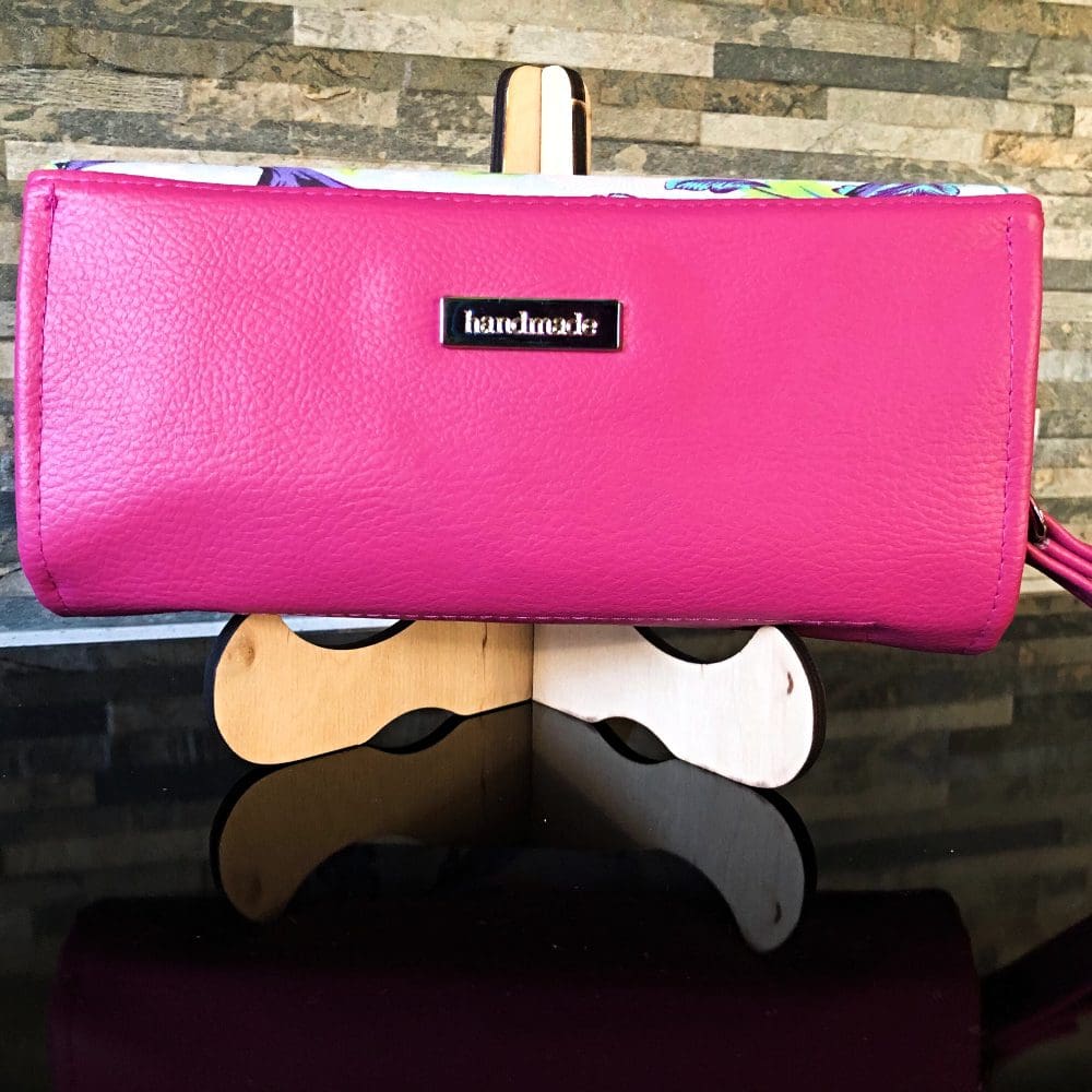 Ladies clutch wallet, back view with pink faux leather on a stand