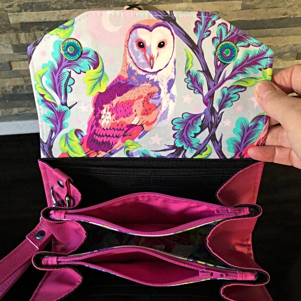 Ladies clutch wallet showing the open inside featuring Tula Pink Owl print flap with pink faux leather body and black fabric.