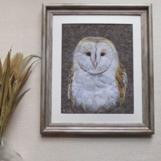 An original handmade needle felted wool picture of a barn owl on a grey background in a silver antique wood effect frame.