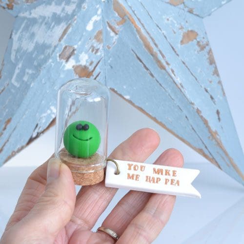 Little clay pea under a glass cloche with a clay label 'You make me hap pea'