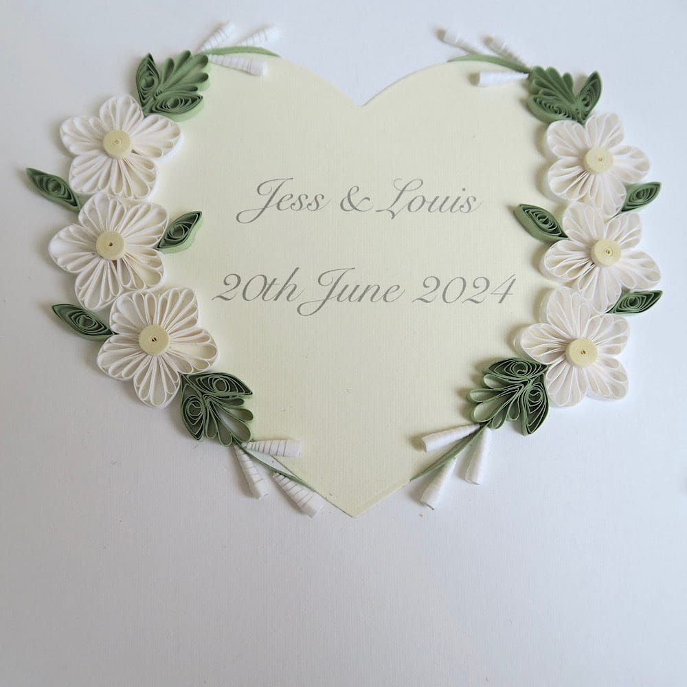 Close up of the cover of a personalised wedding guest book decorated with quilled flowers