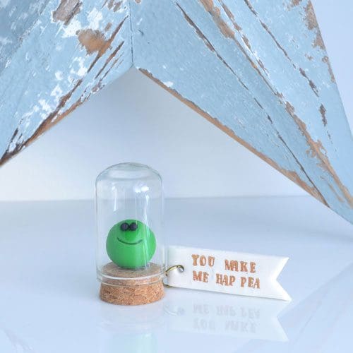 Little clay pea under a glass cloche with a clay label 'You make me hap pea'