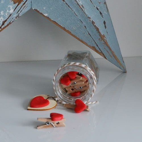 Glass Jar of clay hearts set on pegs to hang photos on the wall
