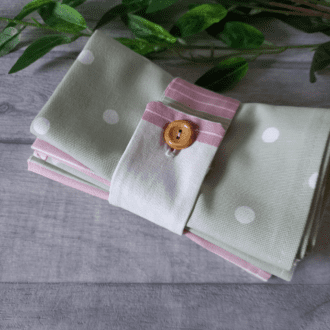 set of four folded pink and green napkins with button cuff