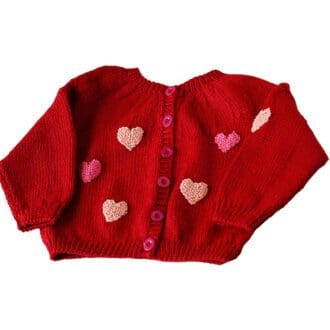 red hand knitted baby cardigan with pink heart appliqués