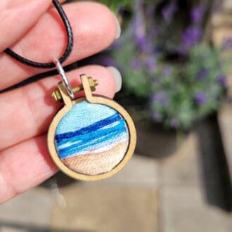 Hand embroidered view of the sea set in a wooden mini hoop pendant 2.5cm on leather cord.