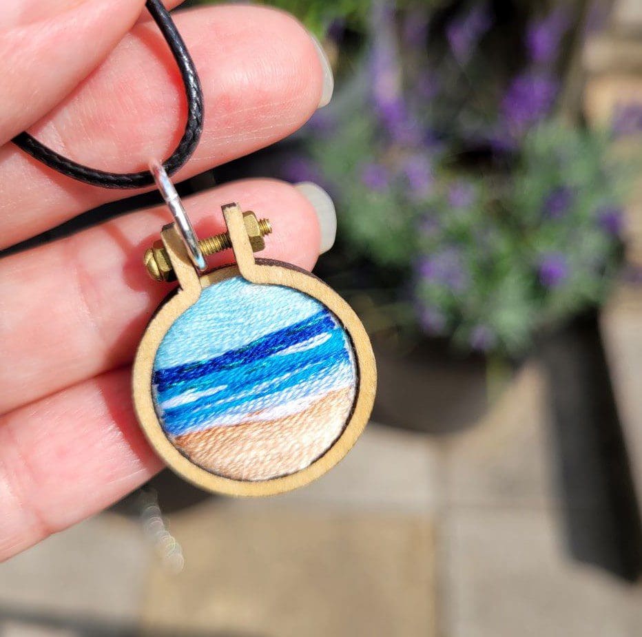 Hand embroidered view of the sea set in a wooden mini hoop pendant 2.5cm on leather cord.