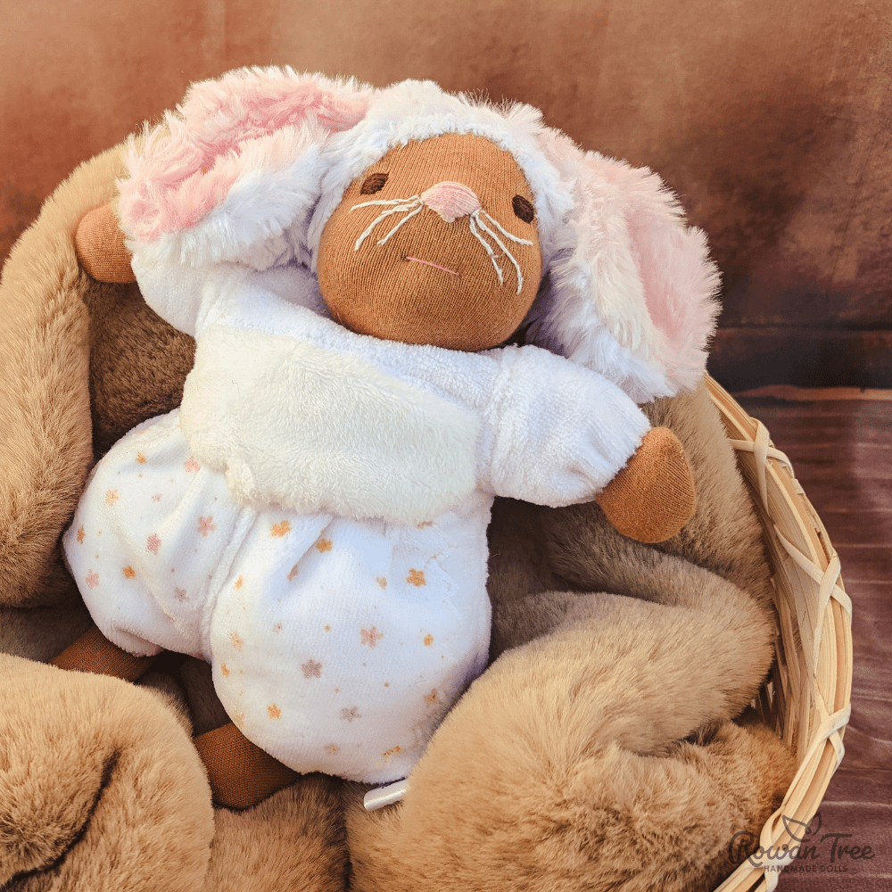 mouse doll with brown skin lying in basket with brown blanket and cinnamon background