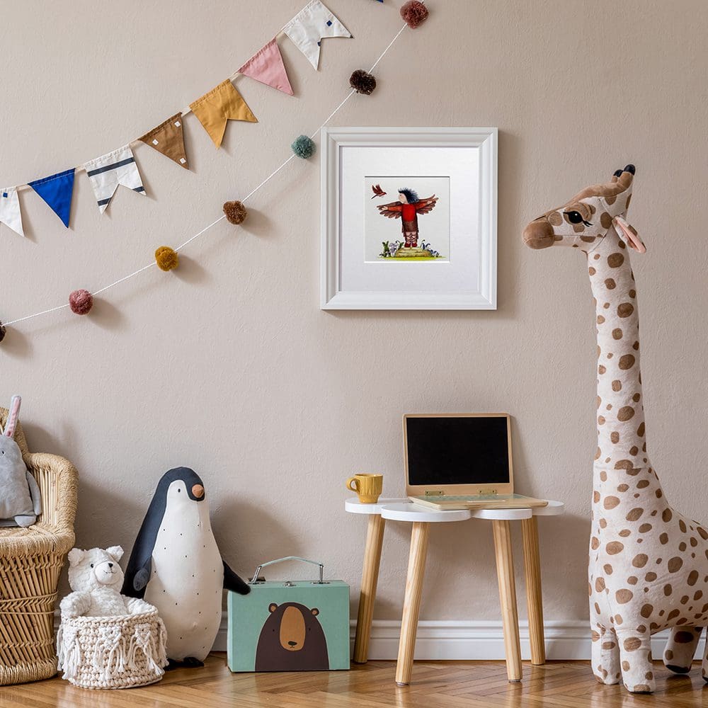 The picture of a young girl dressed as a robin bird with her bird friend is displayed hanging on a nursery wall.