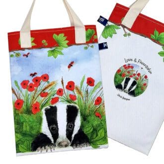 Wildlife bookbag featuring a young badger cub resting amongst the green grass, leaves and red poppies on the front and a love and friendship logo on reverse. Red trim on top with chestnut tree branch decoration and pale cream cotton handles