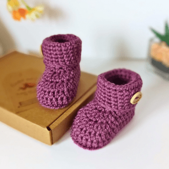 A pair of handmade crochet baby booties in a shade of purple called grape. They come in sizes newborn, 0-3 and 3-6 months made from acrylic yarn ehich is very soft, they make a great baby boy or girl gift
