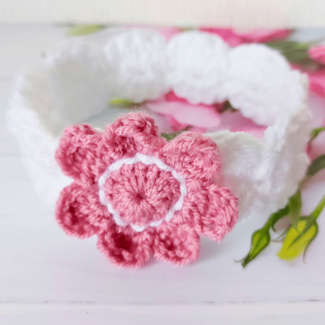 A white crochet hairband with a vintage peach flower attached to the front