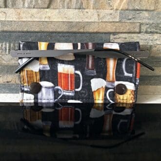 Gently padded fabric glasses holder in a beer themed fabric with caramel cotton lining. Closes with brown kam-snaps