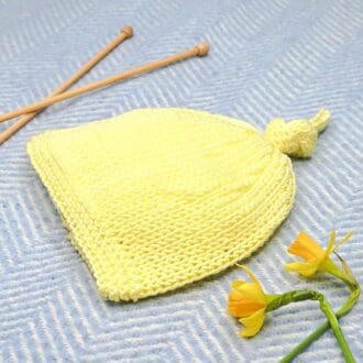 Lemon yellow curly top pixie knitted hat for a newborn baby.